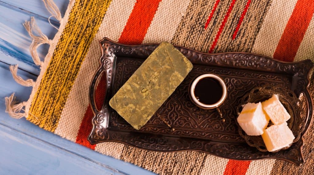 Lys Marok hash anrettet på dekorativ bakke med kaffe og lyse søde stykker, som understreger en klassisk, varm og marokkansk-inspireret stemning.