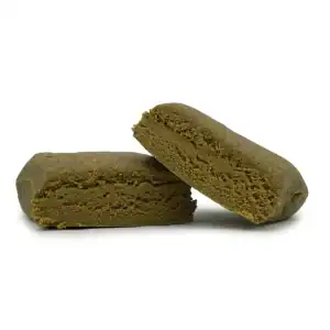 Bubble hash THCa hash i to delte stykker med mørk yderside og blød, porøs struktur på lys baggrund.